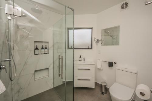 a white bathroom with a shower and a toilet at Smith House in Whanganui