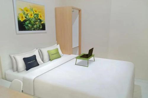 ein weißes Bett mit einem Stuhl und einem Laptop darauf in der Unterkunft Urbanview Syariah Utami Inn Garut by RedDoorz in Garut