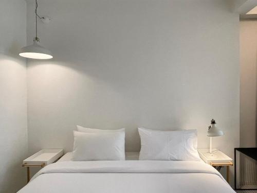 a white bed with white sheets and pillows at POR Santitham in Chiang Mai