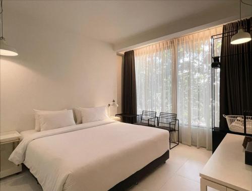 a bedroom with a white bed and a large window at POR Santitham in Chiang Mai