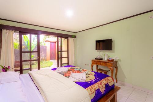a bedroom with a bed and a table and a television at Pacung Indah Hotel & Restaurant by ecommerceloka in Bedugul