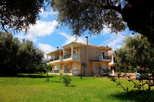 a large yellow house with a green yard at Arodo in Lefkada Town