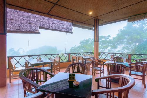 un ristorante con tavoli e sedie su un balcone di Pacung Indah Hotel & Restaurant by ecommerceloka a Bedugul