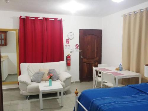 Cette chambre comprend un canapé, une table et un rideau rouge. dans l'établissement Dominican Suite 21, Amazing Apt/Studio (DS21), à San Felipe de Puerto Plata