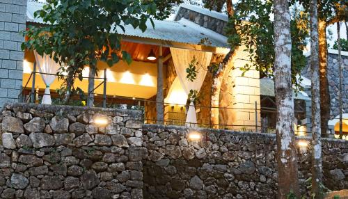 a stone wall in front of a building with lights at SpiceTree Rajakumari in Munnar