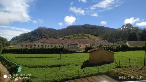 a farm building in the middle of a green field at Forest Gate in Ooty