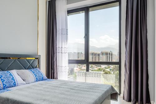 Un dormitorio con una cama y una ventana grande. en Heaven 10, en Almaty