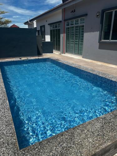 a blue swimming pool in front of a house at Villa Pool Kepala Batas in Kampong Hilir