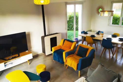 sala de estar con sillas amarillas y azules y TV en Agréable maison moderne, entre campagne et mer !, en Dozulé