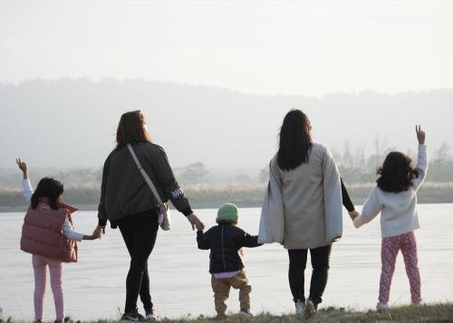 a family of four holding hands by the water at Sanctuary Chitwan National Park in Chitwan