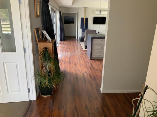 a hallway with two potted plants on a hard wood floor at Large stand alone home with two living areas. in Taupo