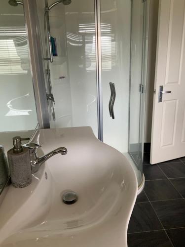 uma casa de banho com um lavatório branco e um chuveiro em Large stand alone home with two living areas. em Taupo