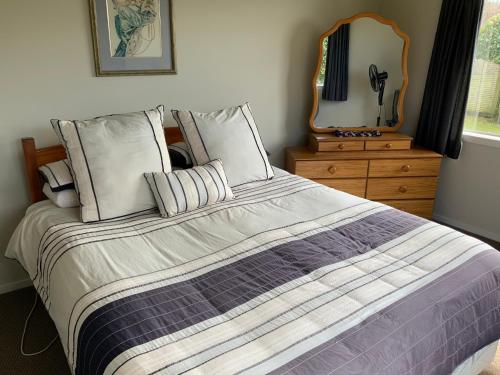 a bedroom with a bed with a mirror and a dresser at Large stand alone home with two living areas. in Taupo