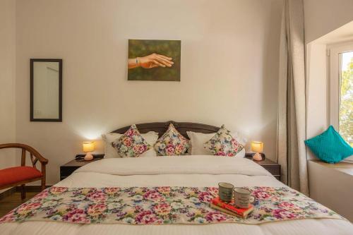a bedroom with a bed with a floweridered blanket on it at StayVista at Pines & Spruce - Exclusive getaway in Lansdowne