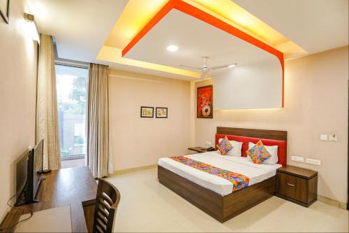 um quarto com uma cama e uma televisão em FabHotel Pine Tree em Noida