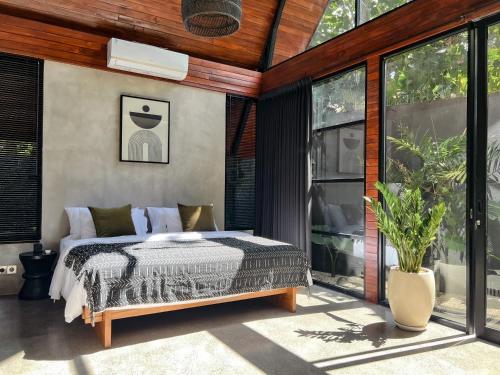 Schlafzimmer mit einem Bett und großen Fenstern in der Unterkunft Villa Keliki in Munggu