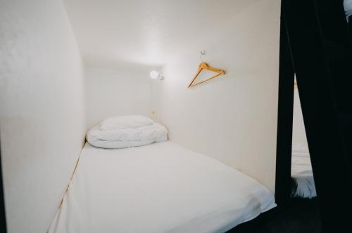 Habitación blanca con cama y percha en la pared en unito light SHIMBASHI, en Tokio
