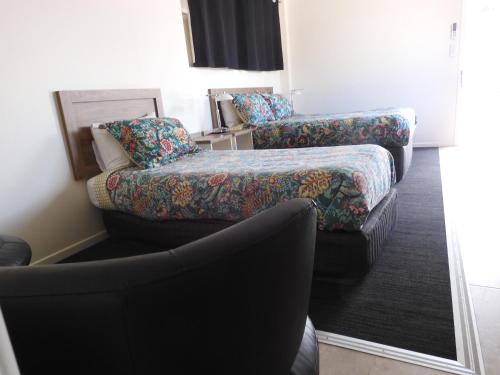 Habitación de hotel con sofá y silla en Dalby Parkview Motel en Dalby