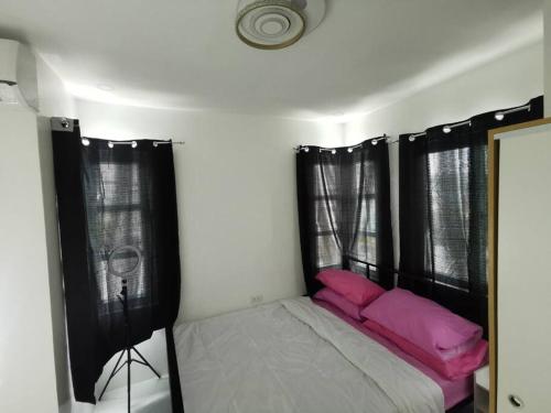 a small bedroom with a bed with pink pillows at JRLB PLACE - Accommodation in Concepcion, Tarlac in Concepcion