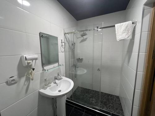 a white bathroom with a sink and a shower at Aurora Hotel in Tashkent