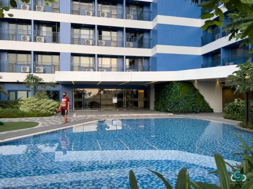a woman stands next to a swimming pool in front of a building at Staycation by Ness in Ayala Makati in Manila