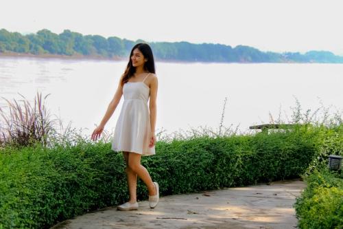 a woman in a white dress standing next to a lake at River Tree Resort in Chiang Khan