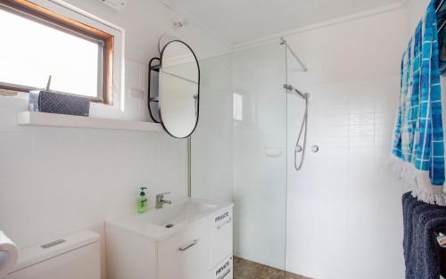 a bathroom with a shower and a sink and a mirror at Cliffs End Beach Shack 105 Gold Coast Drive in Carrickalinga