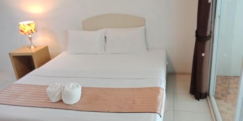 a bedroom with a bed with two white shoes on it at โรงแรมเวลลิงตัน in Ban Chak Phai