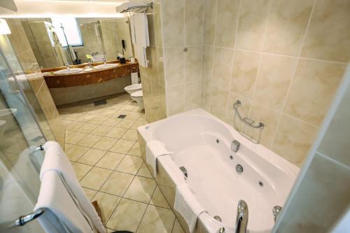 a bathroom with a tub and a toilet and a sink at Al Maha Arjaan by Rotana in Abu Dhabi