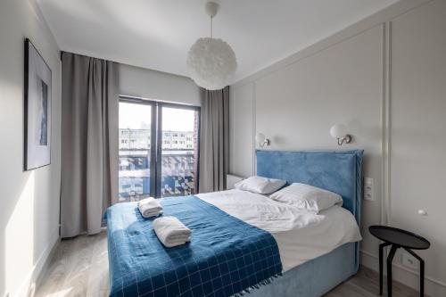 a bedroom with a blue bed with towels on it at Apartament blisko Starego Miasta z widokiem na Motławę in Gdańsk
