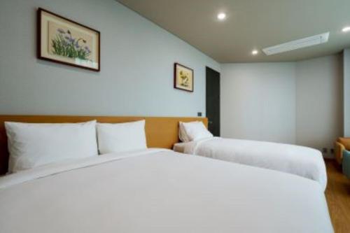 a bedroom with two beds with white pillows at Kwangsu Hotel Haeundae in Busan