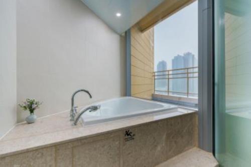 a bathroom with a bath tub with a window at Kwangsu Hotel Haeundae in Busan