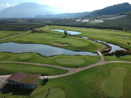 an aerial view of a golf course with a lake at The Lodge Sporthotel - Golfclub Eppan in Appiano sulla Strada del Vino