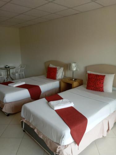 a room with two beds with red and white pillows at โรงแรมเวลลิงตัน in Ban Chak Phai