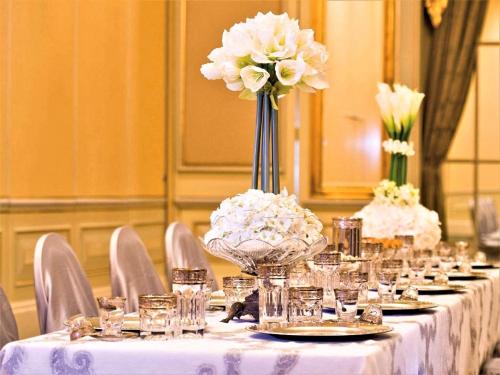 a long table with a vase of flowers on it at Mövenpick Hotel Al Khobar in Al Khobar