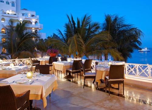 a restaurant with white tables and chairs and palm trees at Suites at Pueblo Bonito Rose' and Spa Cabo San Lucas in Cabo San Lucas