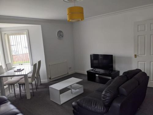 a living room with a couch and a table and a tv at Teith court apartment with private parking. in Stirling