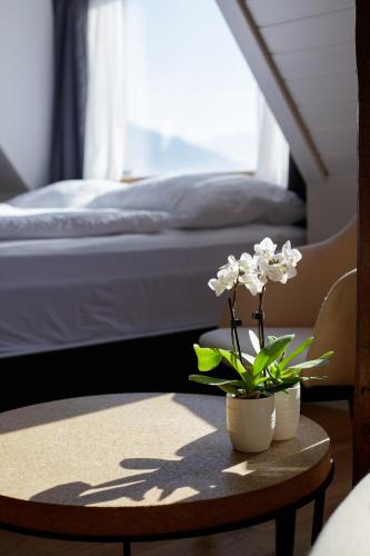 a table with two white flowers on top of a bed at BERG & BERG APARTMENTS - Spiez Self-Check-in in Spiez