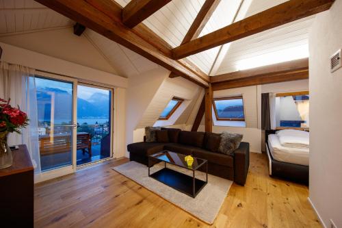 a living room with a couch and a bed and windows at Welcome Apartments Spiez in Spiez