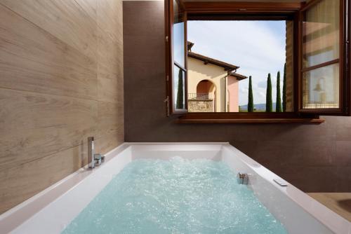a bath tub filled with water in front of a window at Borgobrufa Spa Resort Adults Only in Brufa
