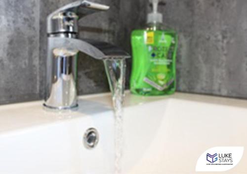 a sink with a faucet and a green bottle of soap at Luke Stays - Alum Waters in New Brancepeth