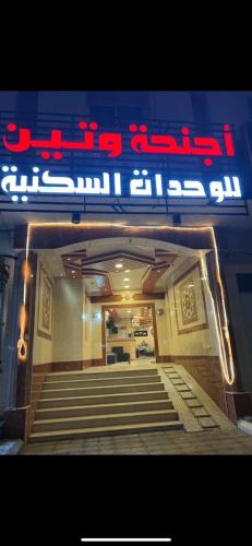 a sign for a restaurant with stairs in front at أجــنــحــة وتــيــن in Al Madinah