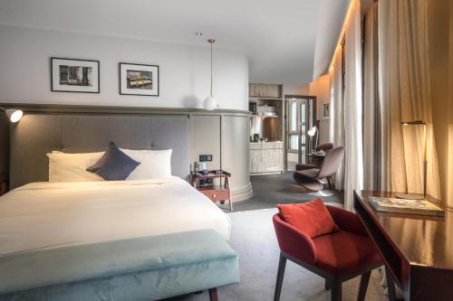 a bedroom with a large bed and a red chair at Ann Siang House, The Unlimited Collection managed by The Ascott Limited in Singapore