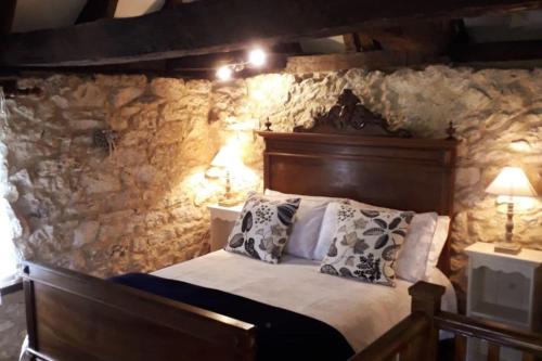 une chambre avec un lit avec un mur en pierre dans l'établissement Labarthe Gites Pigeonnier, à Saint-Aubin-de-Cadelech