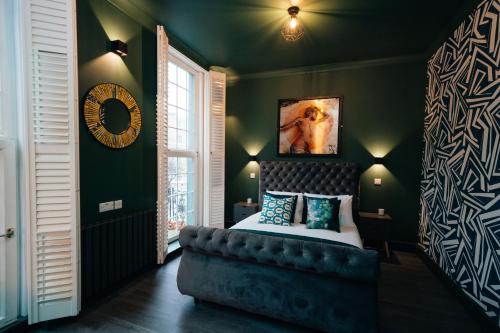 a bedroom with green walls and a bed with a black headboard at The Rokxy Townhouse & Residences - Kings Cross in London