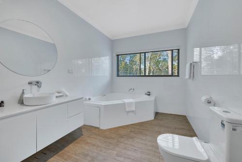 a white bathroom with a sink and a mirror at 27 Rows on Hermitage in Pokolbin