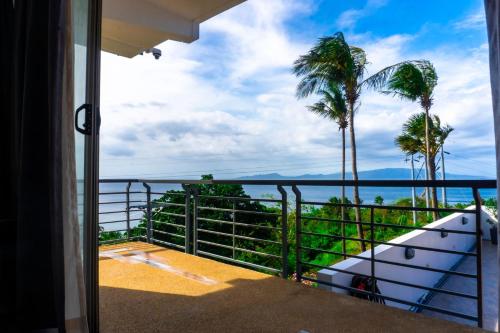 a balcony with a view of the ocean and palm trees at AV Suites in Puerto Galera