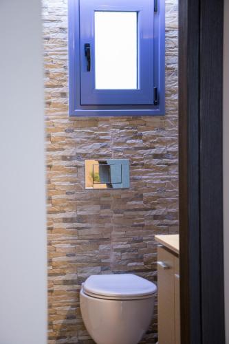 a bathroom with a white toilet and a brick wall at Luxurious House with backyard in Volos