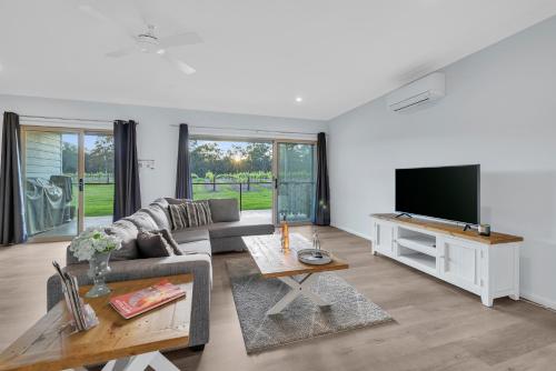 a living room with a couch and a flat screen tv at 27 Rows on Hermitage in Pokolbin