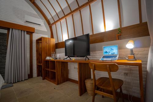 a room with a desk with a laptop and a monitor at Driftwood Lombok in Selong Belanak